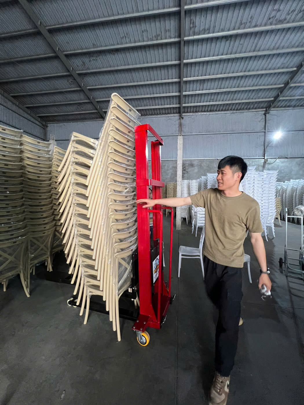 Một người đẩy chồng ghế cao bằng xe nâng MIXU trong kho