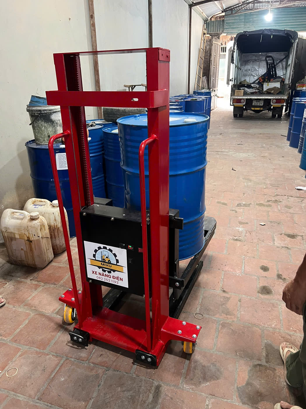 Xe nâng MIXU nâng thùng phuy dầu trong lối đi hẹp, xe tải chờ ở cuối