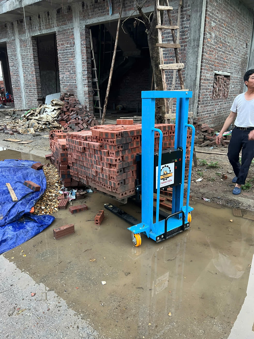 Xe nâng MIXU nâng kiện gạch tại công trình đang xây, nền đất ngập nước