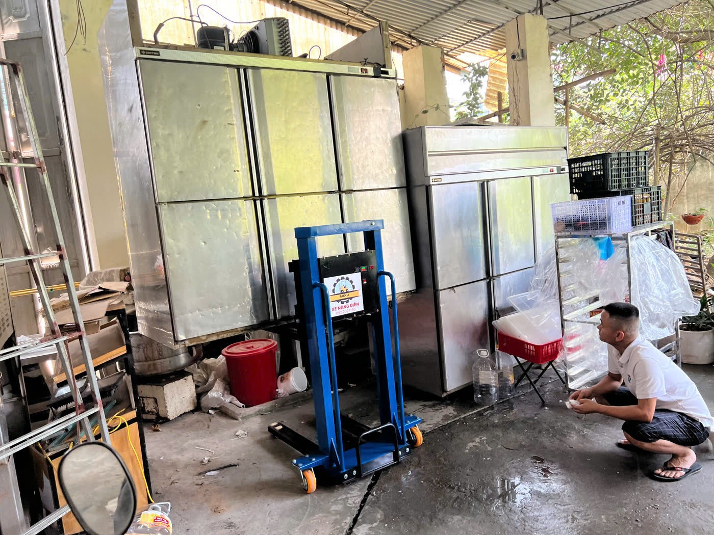 Xe nâng MIXU trong khu bếp chật cạnh tủ đông inox