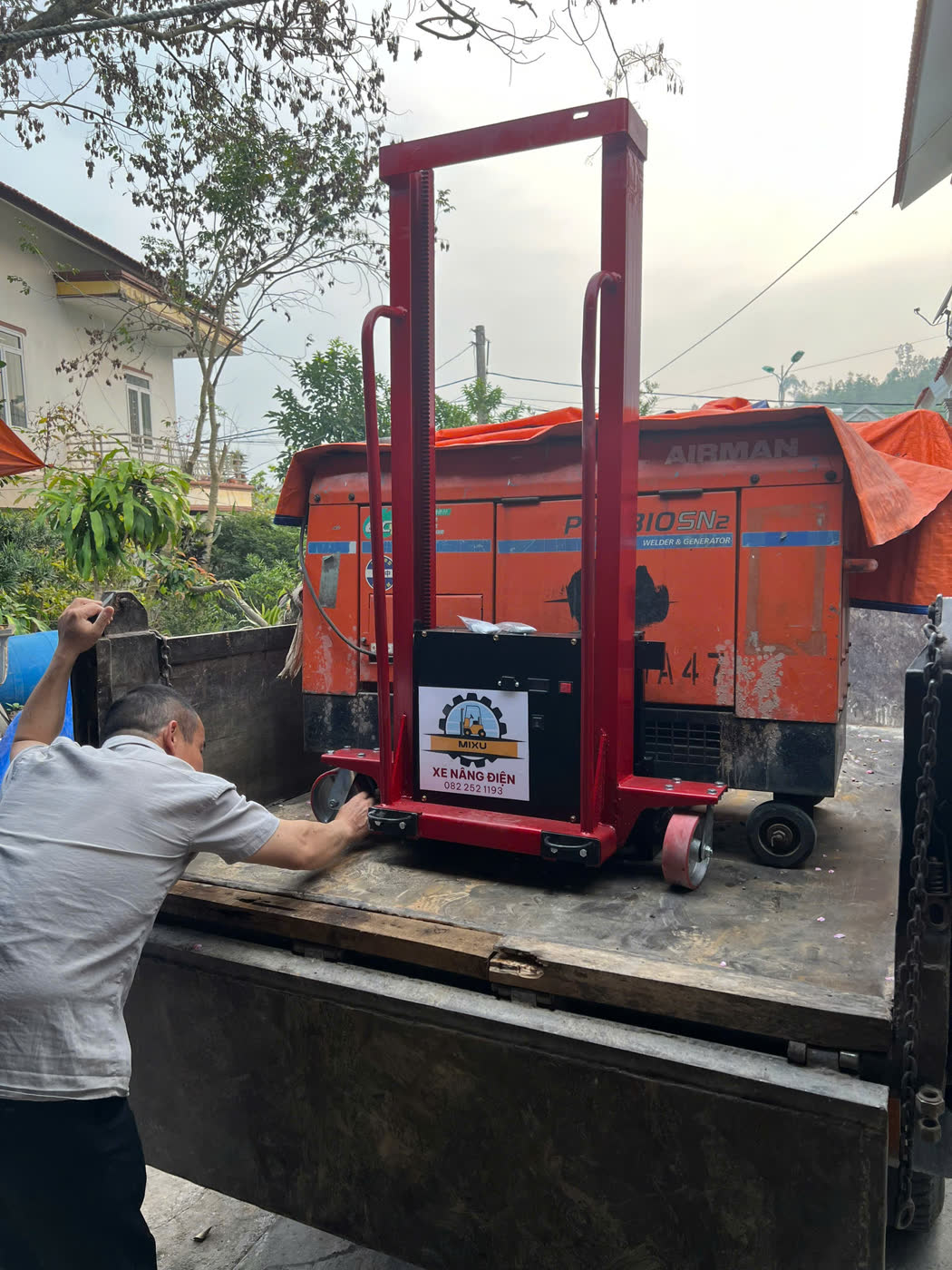 Xe nâng MIXU màu đỏ trên thùng xe tải cạnh máy hàn